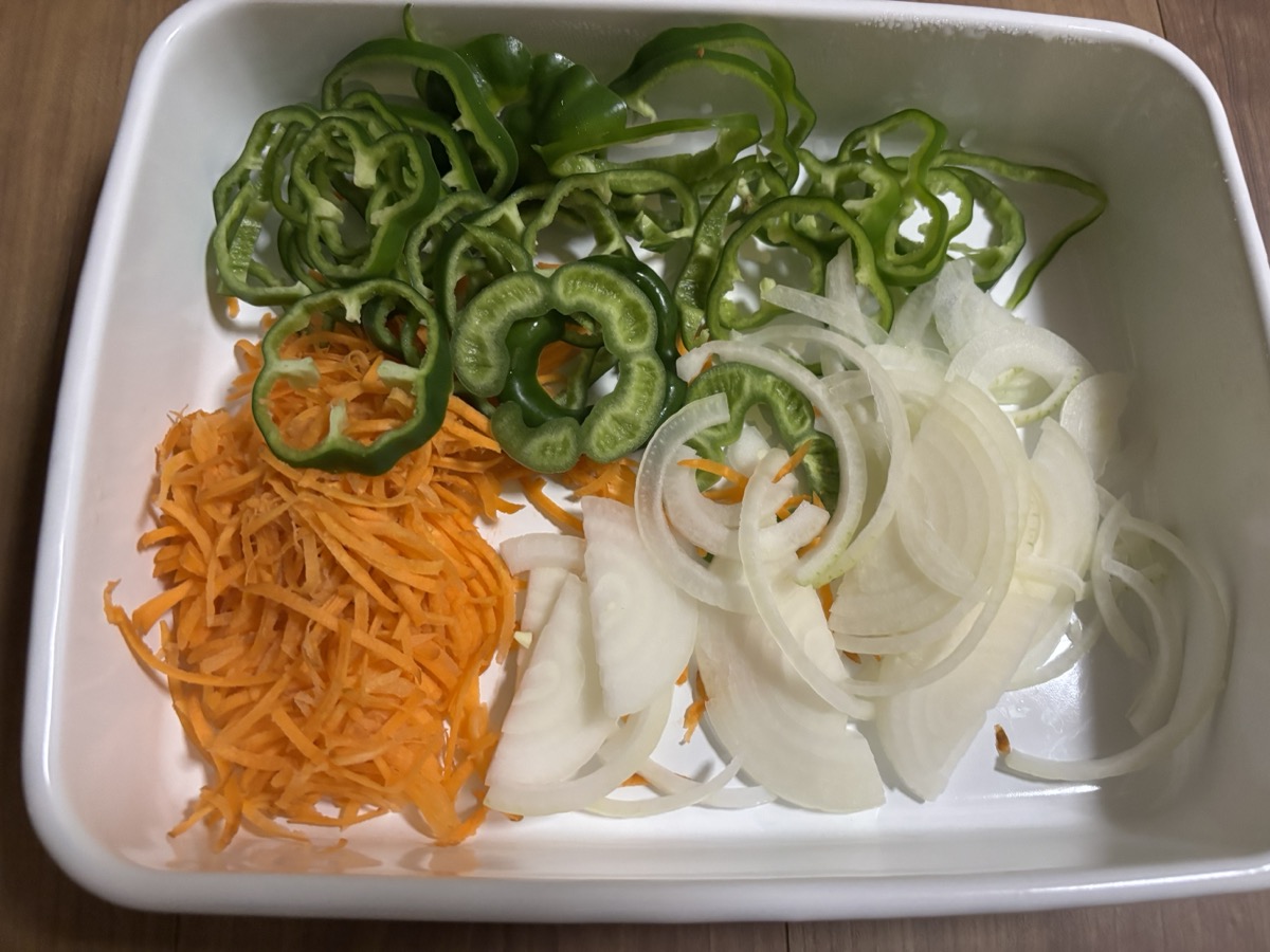 野菜炒めの材料。ピーマン、千切りにんじん、スライス玉ねぎ